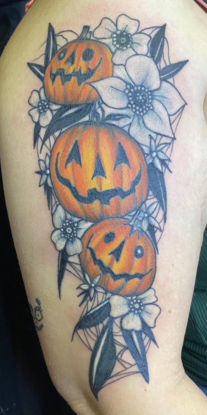 three orange jackolanterns against a black and white floral shoulder piece