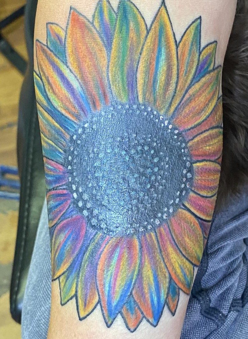 multicolored sunflower done with streaks of blues and oranges and purple around the detailed dotted black sunflower center