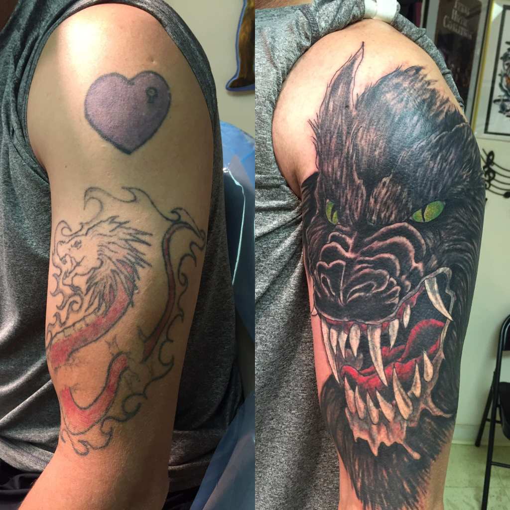 side by side, the before shows a large heart on the shoulder and a line work flaming lion below. The after features a large scale wolf with green eyes and large white teeth with heavy charcoal shading to add the details of the fur covering both previous tattoos.